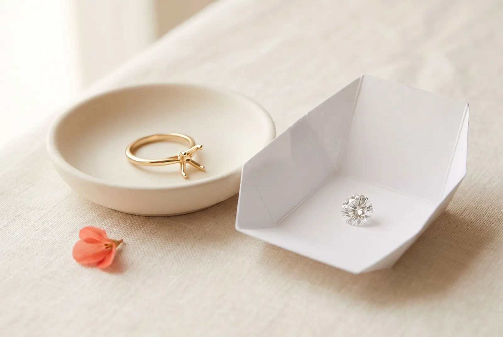 Anillo de compromiso de oro con el engaste vacío en un platito y el diamante suelto guardado aparte en un sobre de papel