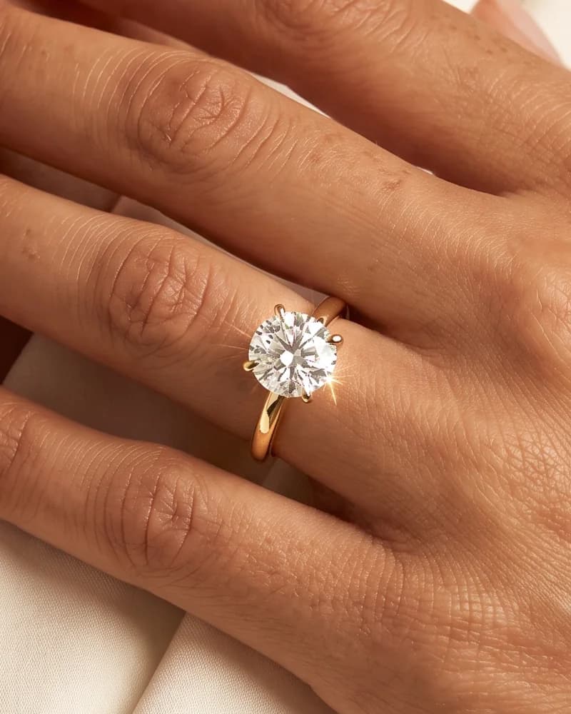 Mano de mujer con un anillo de compromiso solitario de oro amarillo